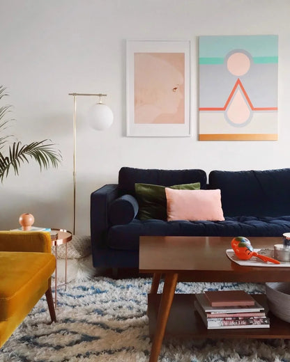 Sillón esquinero Bambú en azul con almohadones rosa y verde, junto a una butaca mostaza