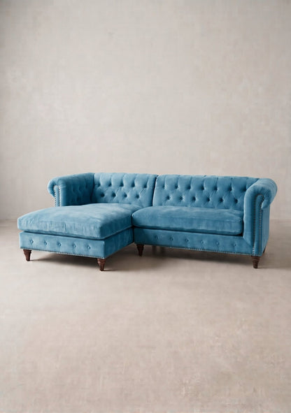 Sillón esquinero Chesterfield en pana antimanchas Océano, forma en L, respaldo capitoné y patas torneadas