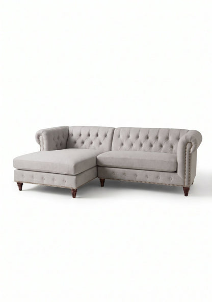 Sillón esquinero Chesterfield en pana antimanchas Plata, con chaise, capitoné y tachas sobre fondo blanco