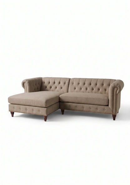 Sillón esquinero Chesterfield en pana antimanchas Stone, con chaise, capitoné y tachas sobre fondo blanco