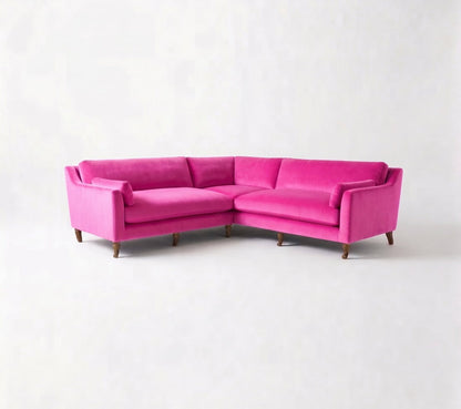 Sillón esquinero Leonelle en pana antimanchas Chicle, forma en L, almohadones y patas torneadas de madera