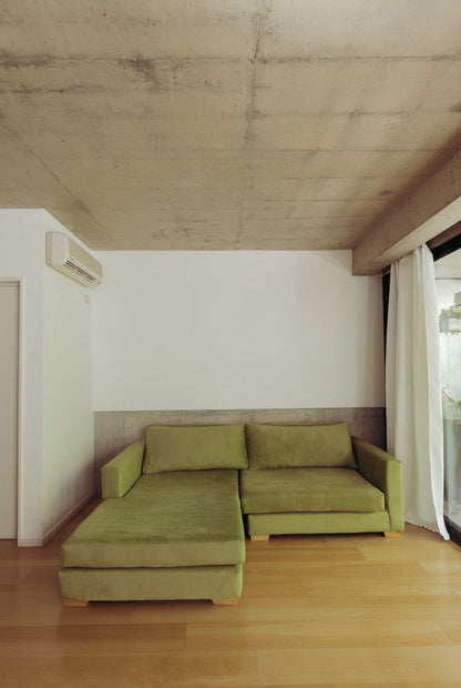 Sillón Esquinero Richard verde con chaise longue en el loft minimalista de Santiago Colinet, con techo de hormigón