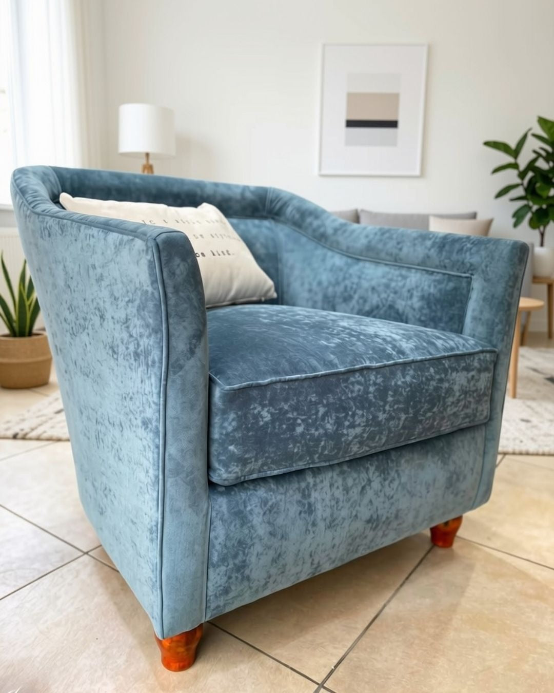Sillón Grand Sofa en terciopelo gris azulado, con respaldo curvo, asiento con vivo y patas de madera, en el living de María