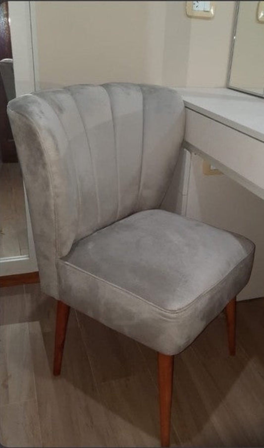 Sillón Matero Alpes gris con respaldo tipo concha de canales verticales y patas de madera, junto al tocador del dormitorio de Romy