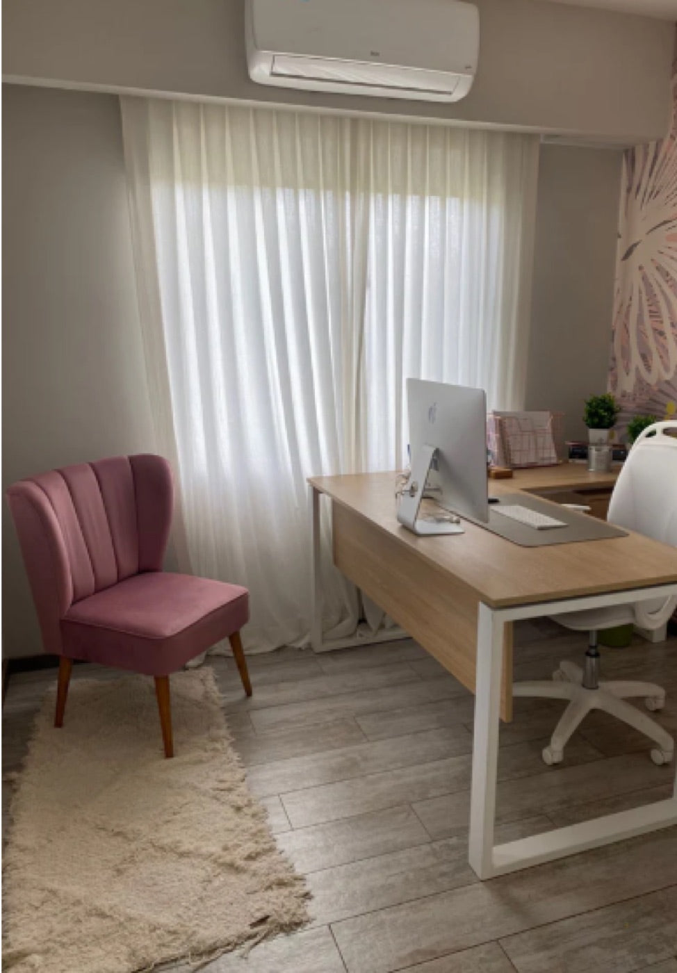 Sillón Matero Alpes tapizado en rosa viejo, con respaldo acanalado y patas cónicas de madera, en el rincón de un consultorio junto al escritorio en L y la cortina de voile