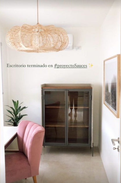 Sillón Matero Alpes rosa terracota junto al escritorio del Proyecto Sauces, con vitrina de hierro y lámpara de fibras naturales