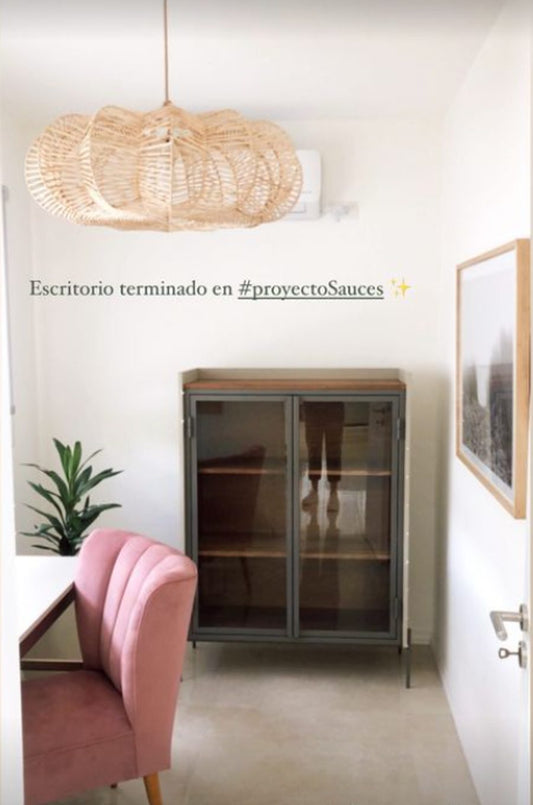 Sillón Matero Alpes rosa terracota junto al escritorio del Proyecto Sauces, con vitrina de hierro y lámpara de fibras naturales