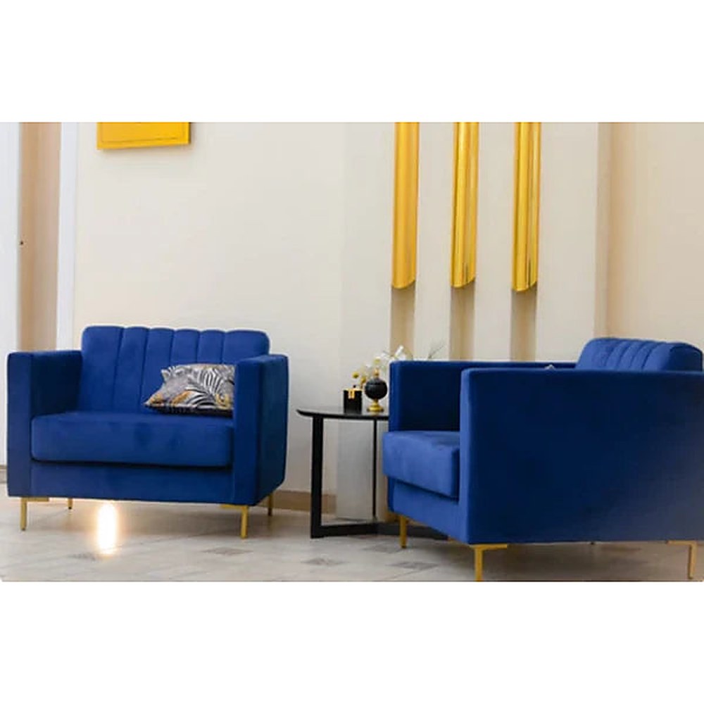 Dos Sillones Mila de pana azul con patas doradas en un living con detalles dorados