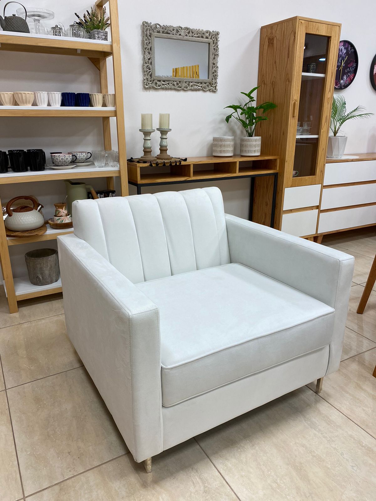 Sillón Mila blanco con respaldo de líneas verticales y patas doradas, en el local De Casas de Firmat