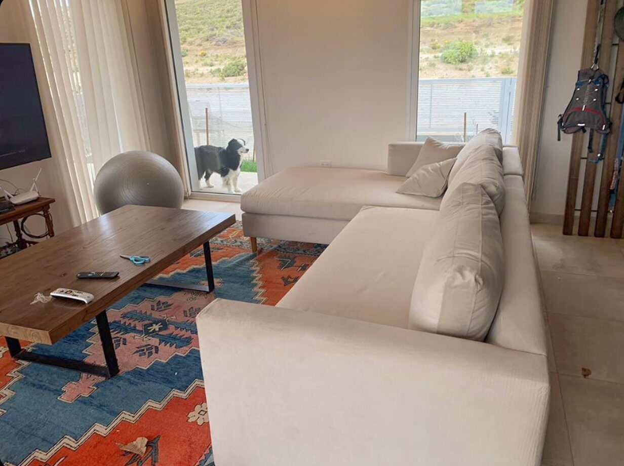 Sillón Esquinero Mirror blanco vista lateral — living con kilim naranja, TV, ventanales y naturaleza exterior — casa de cliente Argentina | Tienda de Banquitos