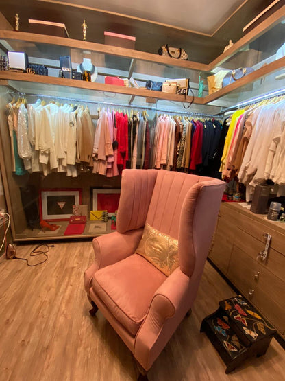 Sillón Mortisia rosa con alas laterales y patas de madera tallada, en el vestidor de Carolina