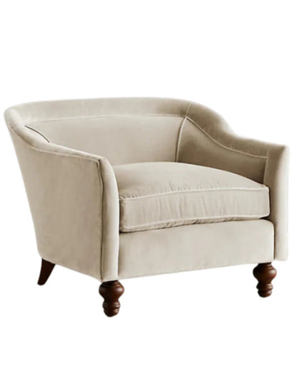 Sillón individual tapizado en color beige claro, con diseño de respaldo envolvente, asiento amplio y patas torneadas de madera oscura.