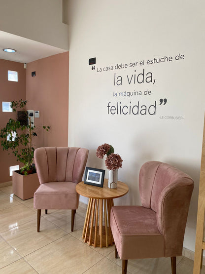 Dos Sillones Matero Alpes en rosa viejo con patas de madera y una mesa auxiliar, en la entrada del local De Casas de Firmat, Santa Fe