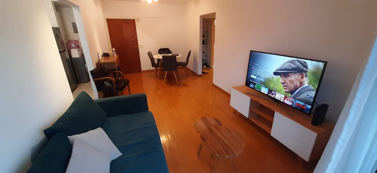 Sofá Bélgica en pana Velutti verde azulado, de líneas rectas, en el living de Hernán con vista al comedor