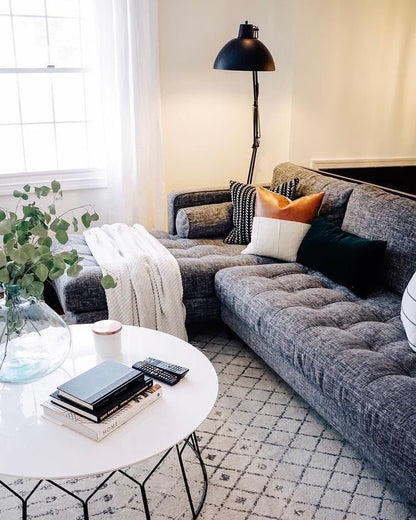 Sofá Chesterfield Capitoné gris en living elegante con lámpara industrial y mesa ratona | Tienda de Banquitos Argentina