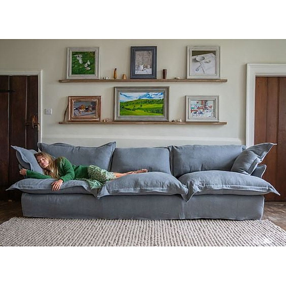 Sofá Comfy con funda de tussor gris azulado y una mujer recostada sobre los almohadones - Tienda de Banquitos