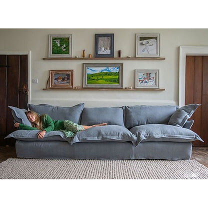 Sofá Comfy con funda de tussor gris azulado y una mujer recostada sobre los almohadones - Tienda de Banquitos