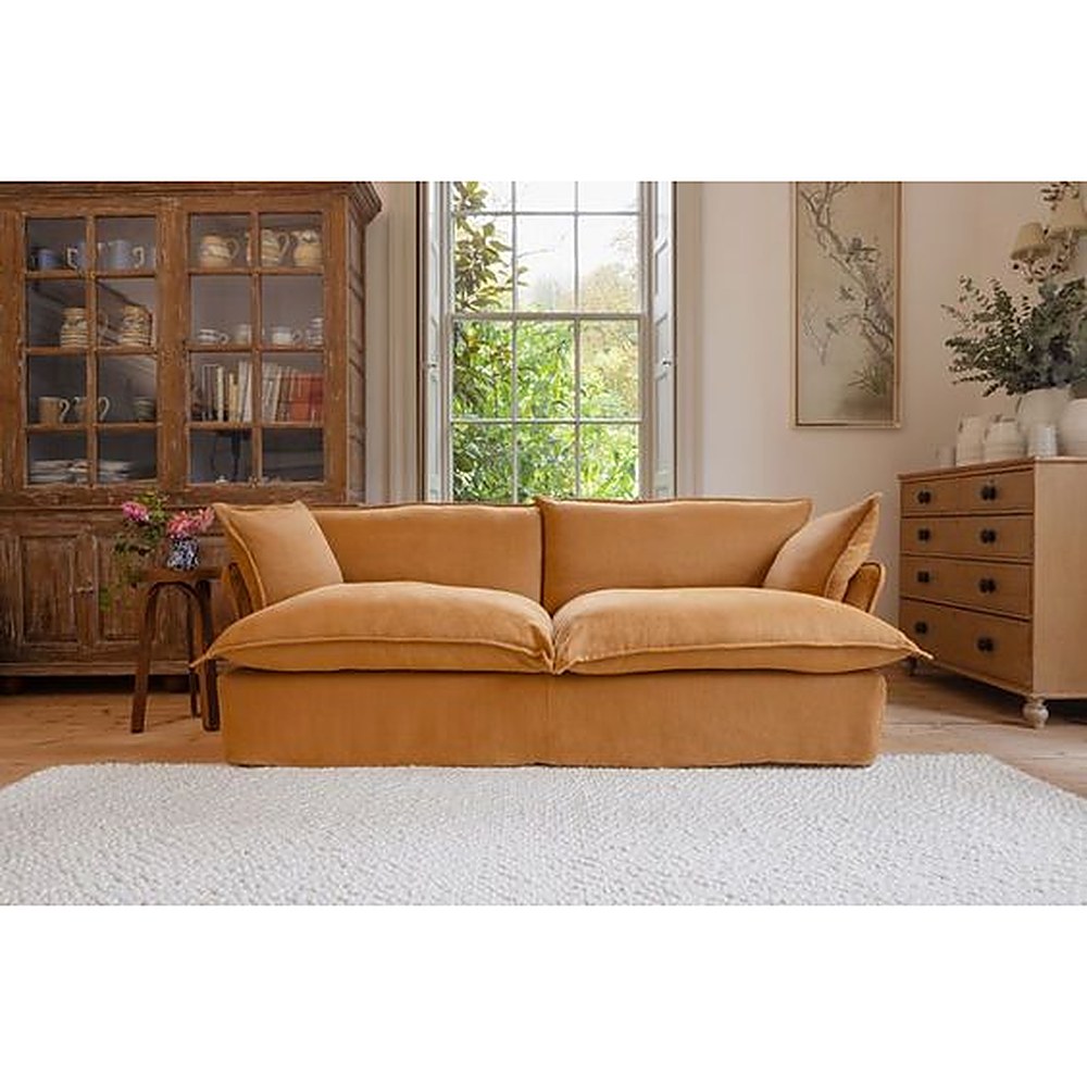 Sofá Comfy con funda de tussor ocre en un living clásico con vitrina de madera y alfombra blanca - Tienda de Banquitos