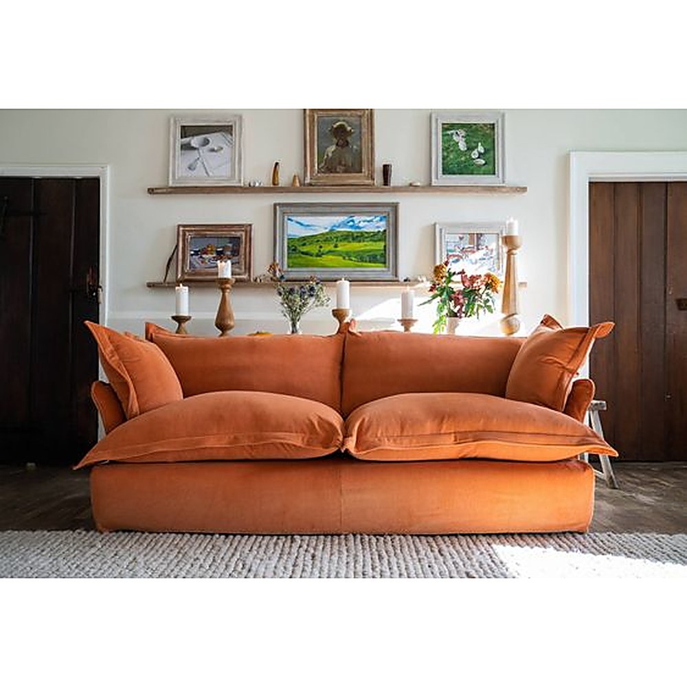 Sofá Comfy con funda de tussor naranja óxido en un living con cuadros y flores - Tienda de Banquitos