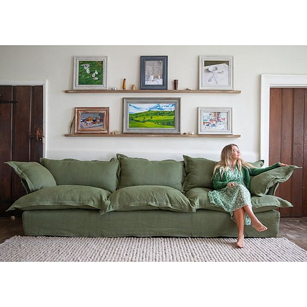 Sofá Comfy con funda de tussor verde y una mujer sentada sobre los almohadones, en un living - Tienda de Banquitos
