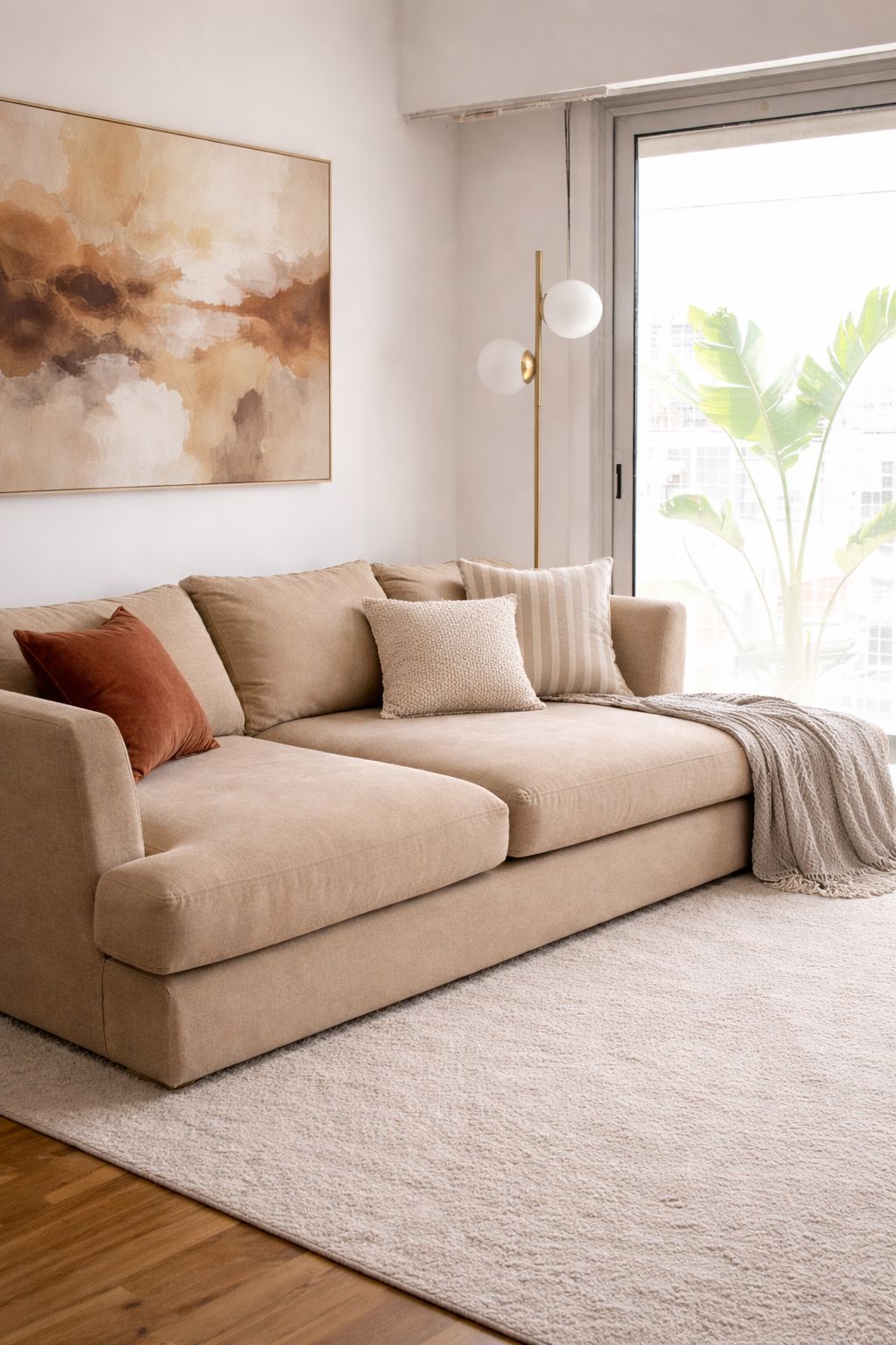 Sofá Elton beige con almohadones sueltos en el living luminoso de Lucía