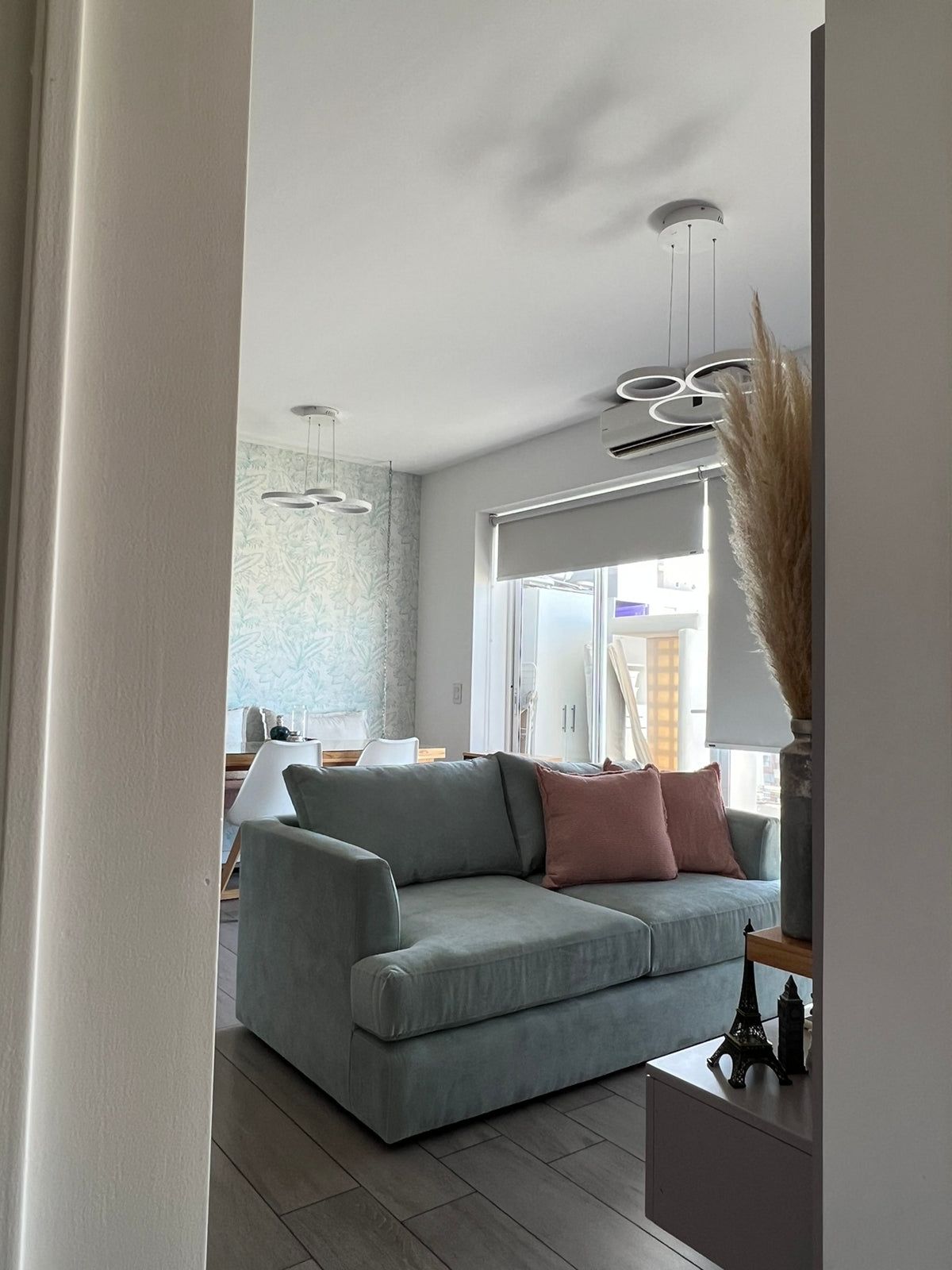 Sofá Elton celeste con almohadones waffle rosa, visto desde el pasillo del living decorado por WN Interiores