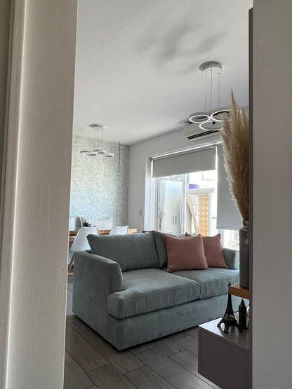 Sofá Elton celeste con almohadones waffle rosa, visto desde el pasillo del living decorado por WN Interiores