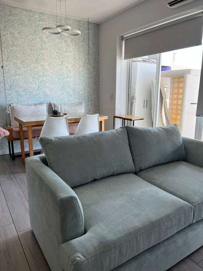 Sofá Elton celeste frente al comedor con empapelado de hojas, en un living decorado por WN Interiores