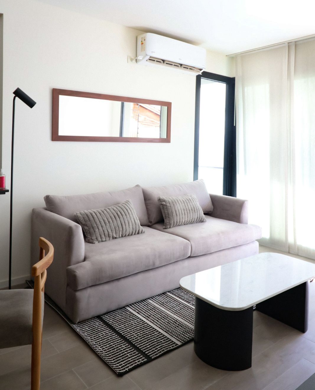Sofá Elton gris lila con almohadones acanalados, mesa de centro de mármol y alfombra rayada, en el living de WN Interiores
