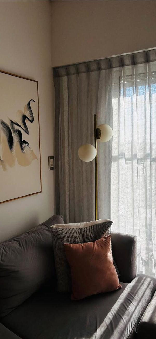 Sofá Elton gris con almohadones y puff al tono, junto al ventanal del living de Tomás