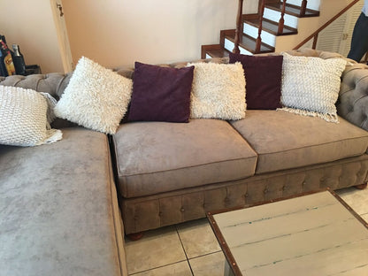 Vista amplia sofá esquinero Chesterfield marrón en living con escalera torneada – Tienda de Banquitos Argentina
