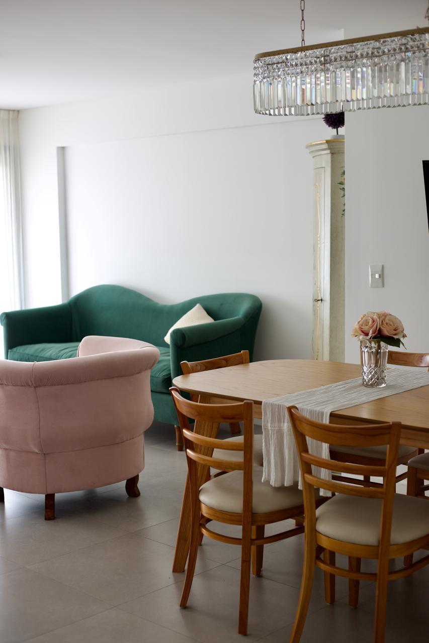 Sofá Flower verde inglés de respaldo curvo y Sillón Brigitte rosa bebé, junto a la mesa del comedor de Vivi