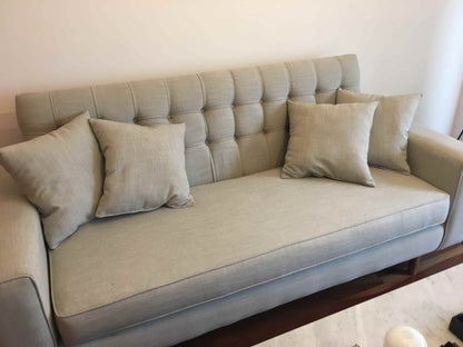 Detalle del respaldo capitoné en canales y el asiento corrido del sofá gris de Verónica