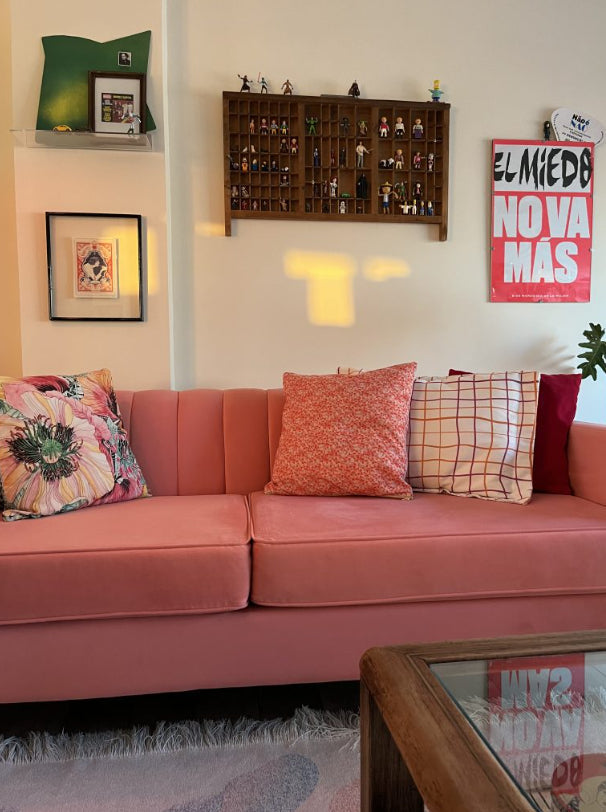 Sofá Mila color coral en el living real de una clienta de Tienda de Banquitos, con almohadones decorativos y estilo ecléctico
