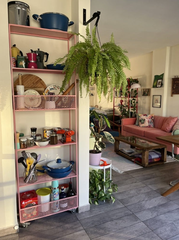 Living con sofá Mila color coral de Tienda de Banquitos, ambientado junto a estantería y plantas
