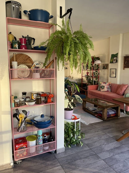 Living con sofá Mila color coral de Tienda de Banquitos, ambientado junto a estantería y plantas