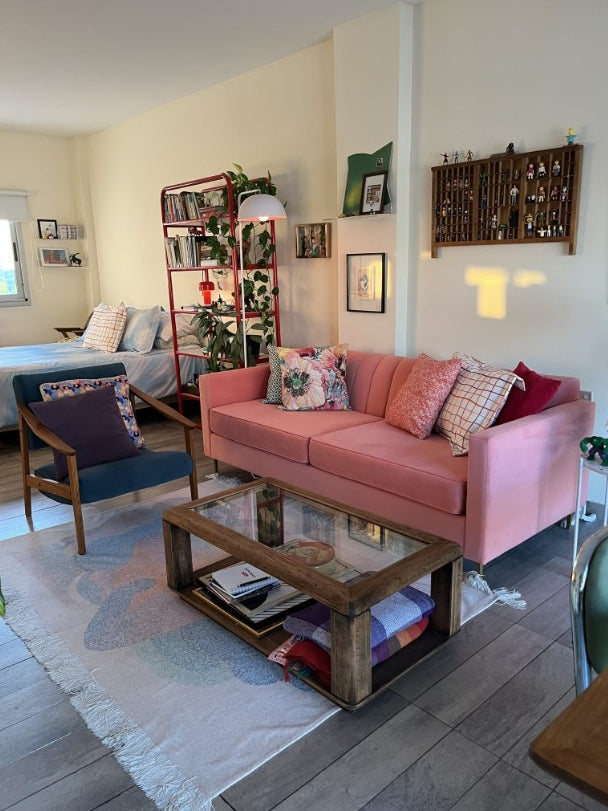 Sofá Mila color coral con almohadones decorativos en el living completo de una clienta de Tienda de Banquitos