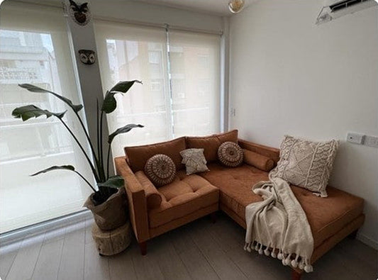 Sofá rinconero terracota con chaise longue de Lorena Barragán, junto a un ventanal con plantas