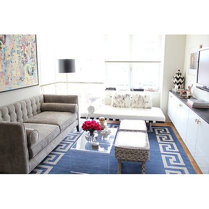 Sofá Valentino gris aterciopelado en un living luminoso con alfombra azul y mesa ratona de acrílico - Tienda de Banquitos