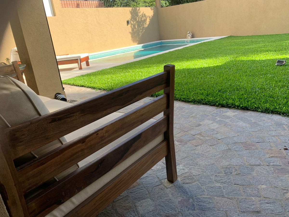 Respaldo de listones de madera del Sofá Verona, con el jardín y la pileta de la casa de Antonella de fondo