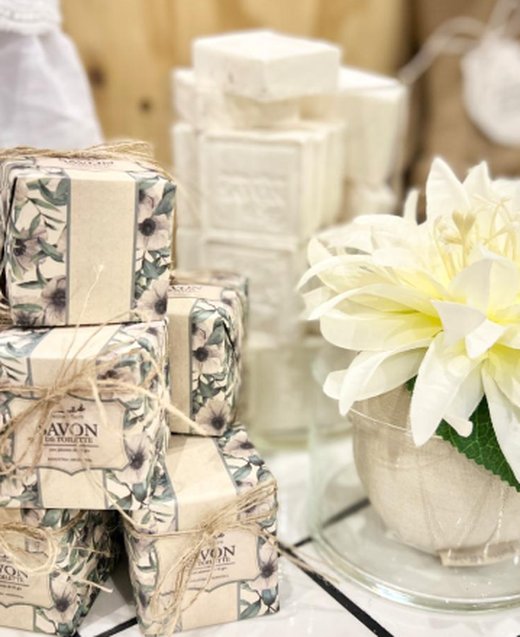 Jabones Anémonas envueltos apilados junto a pastillas blancas y una flor en una mesa de baño