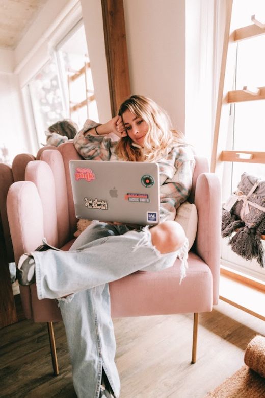 Tupi Saravia con la mano en el pelo, sentada con su notebook en el Sillón Angie rosa