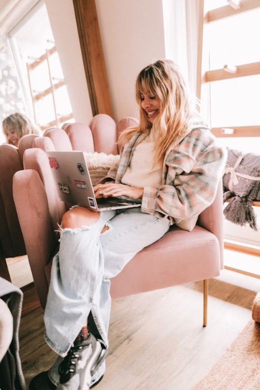 Tupi Saravia mirando la notebook, sentada de costado en su Sillón Angie de terciopelo rosa