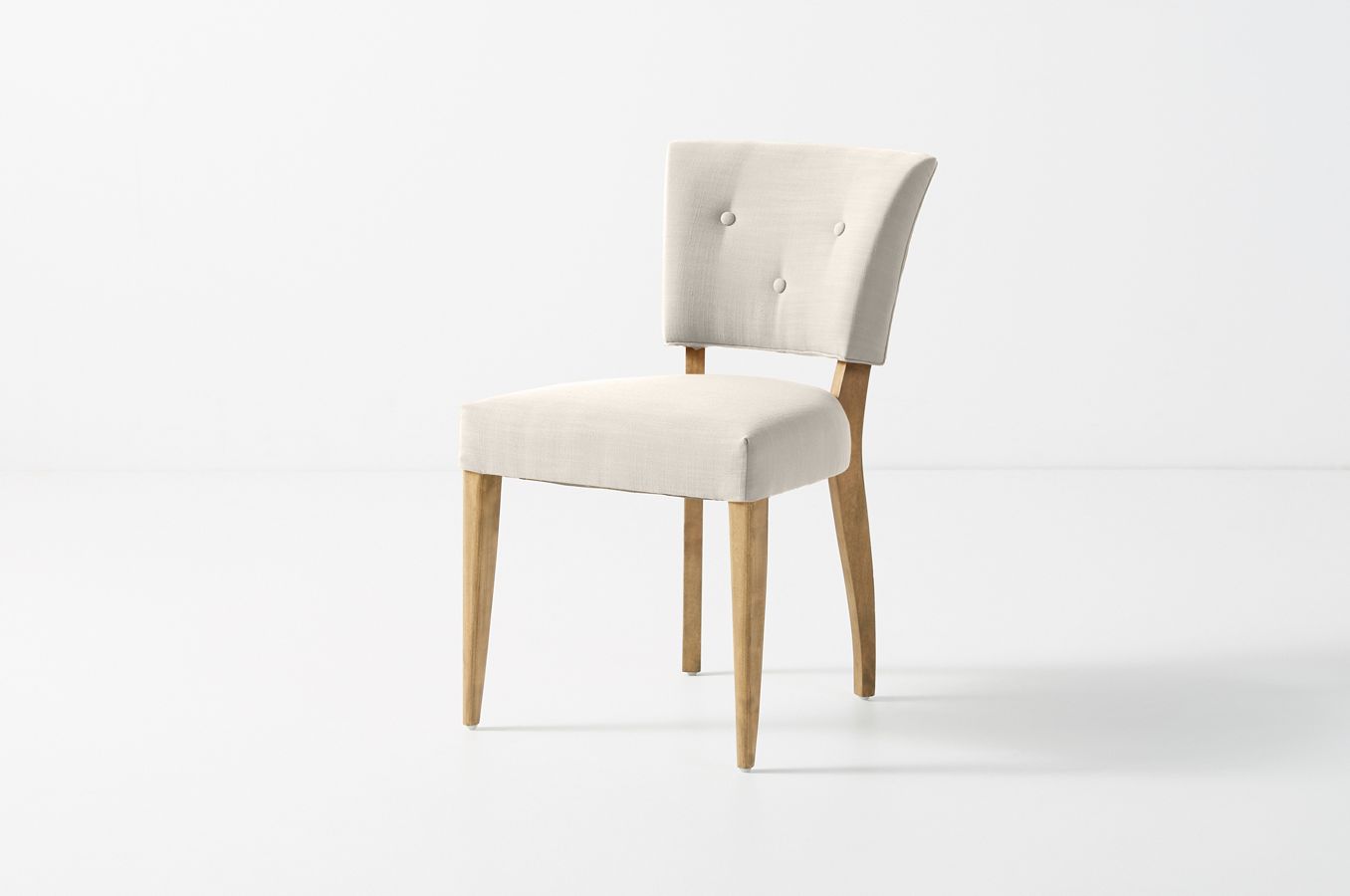 Silla con botoné en el respaldo en pana antimancha importada color crema, con patas de madera lustre roble claro 