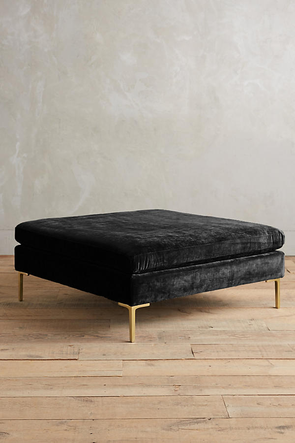 Banqueta rectangular tapizada en con patas doradas. Su diseño compacto y moderno la vuelve ideal para espacios reducidos o como apoya pies.