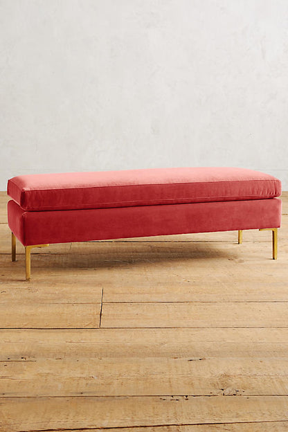 Banqueta de diseño moderno tapizada en rojo con patas metálicas doradas. Ideal para pie de cama, recibidores o livings.