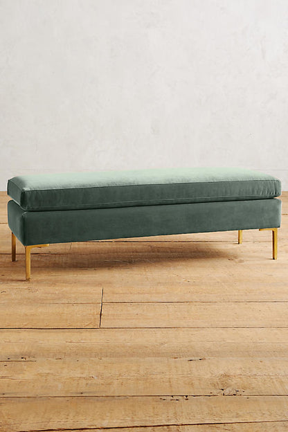 Banqueta de diseño moderno tapizada en verde con patas metálicas doradas. Ideal para pie de cama, recibidores o livings.