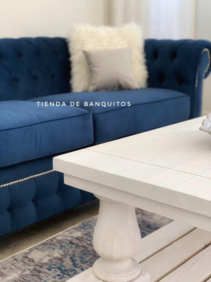Juego de sillones con tapizado capitoné en tonos azul marino y gris, de diseño elegante y clásico, ubicados en un living luminoso con decoración sofisticada