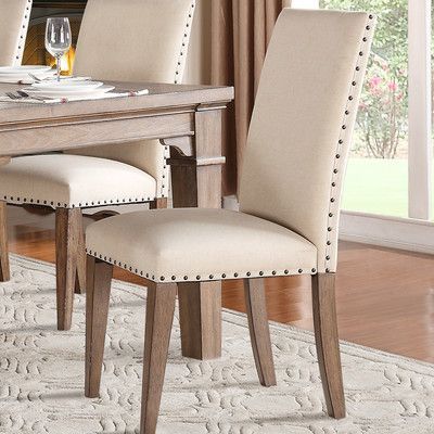 Silla de comedor lisa con tachas color óxido en color crema, con patas de madera lustre roble claro