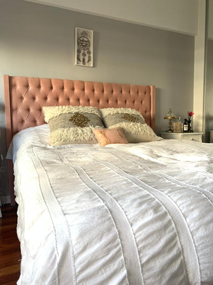 Respaldo alto tapizado en terciopelo rosa suave con diseño capitoné de botones, que aporta un toque elegante y acogedor al dormitorio